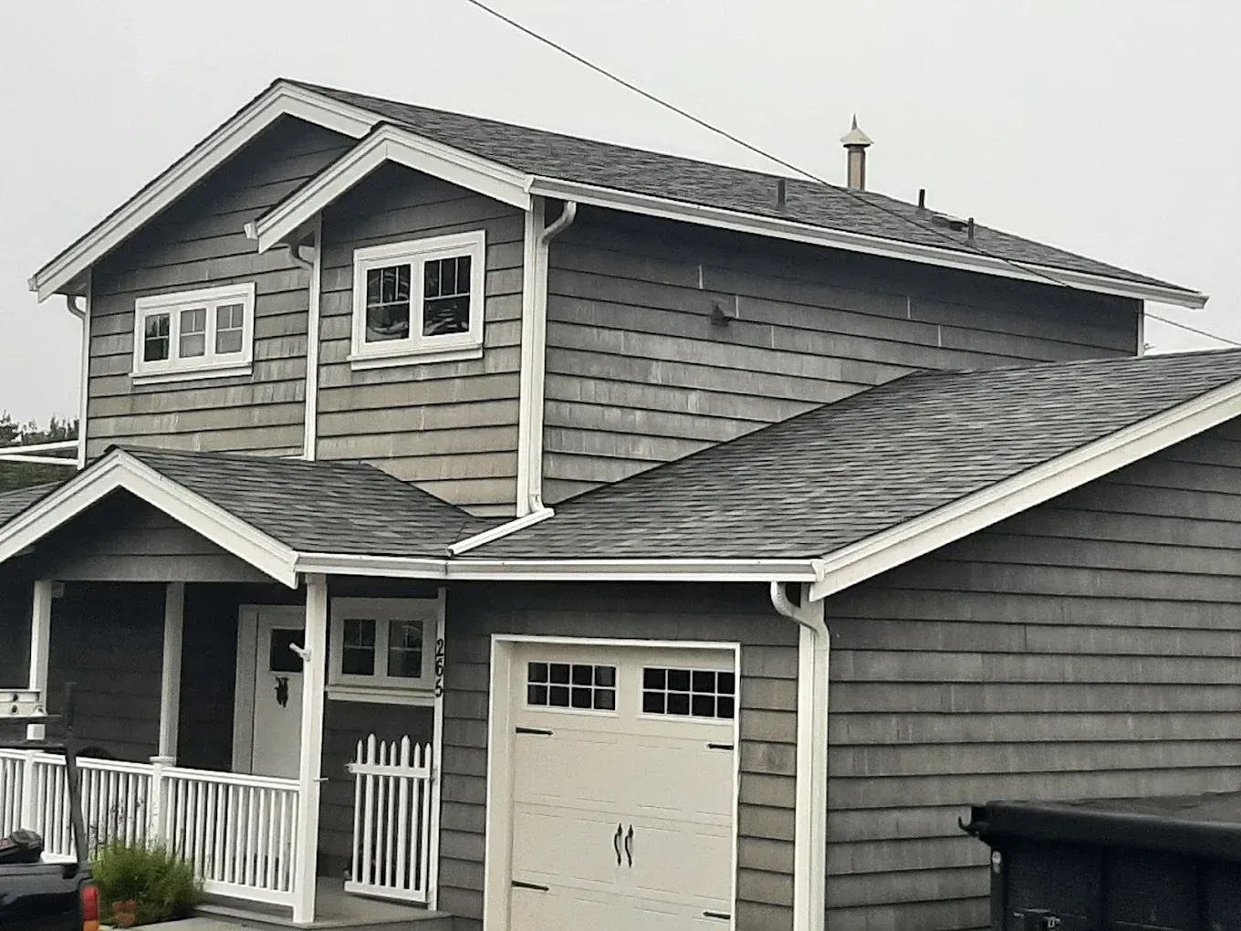 Gray two-story house with white trim, gabled roof, and garage.