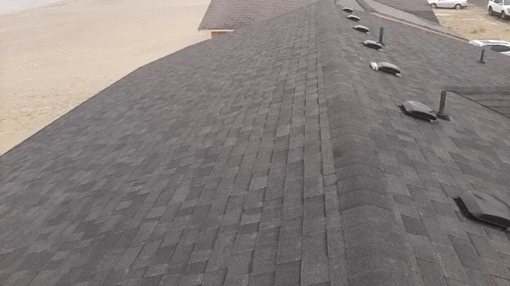 Dark gray asphalt shingle roof with multiple black vent pipes.
