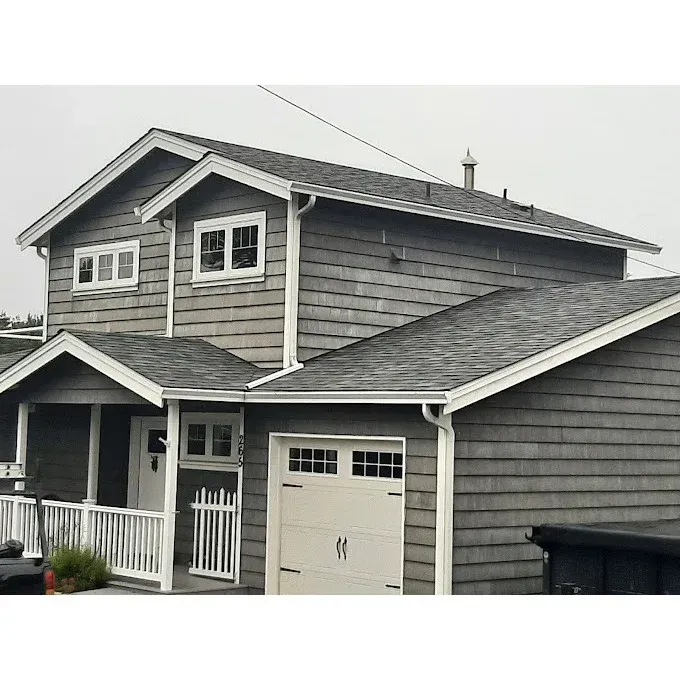 Gray two-story house with white trim, porch, and garage on a cloudy day.