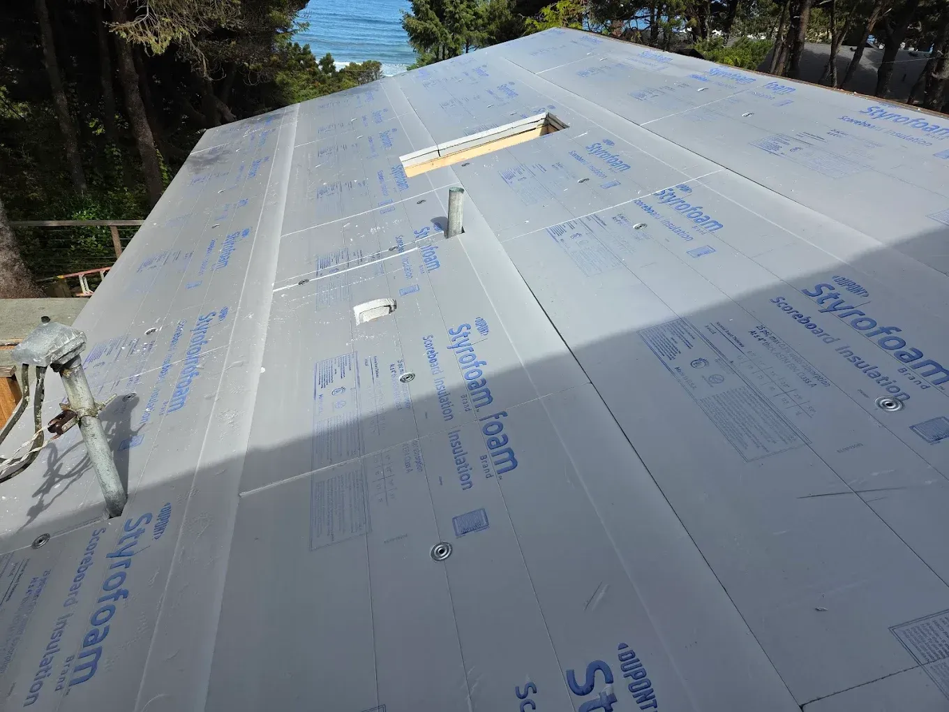 A partially covered roof with Styrofoam insulation panels and fasteners.