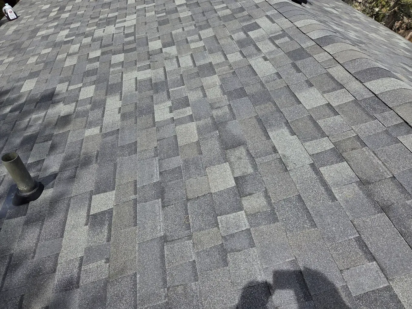 Gray asphalt shingle roof with a vent pipe.