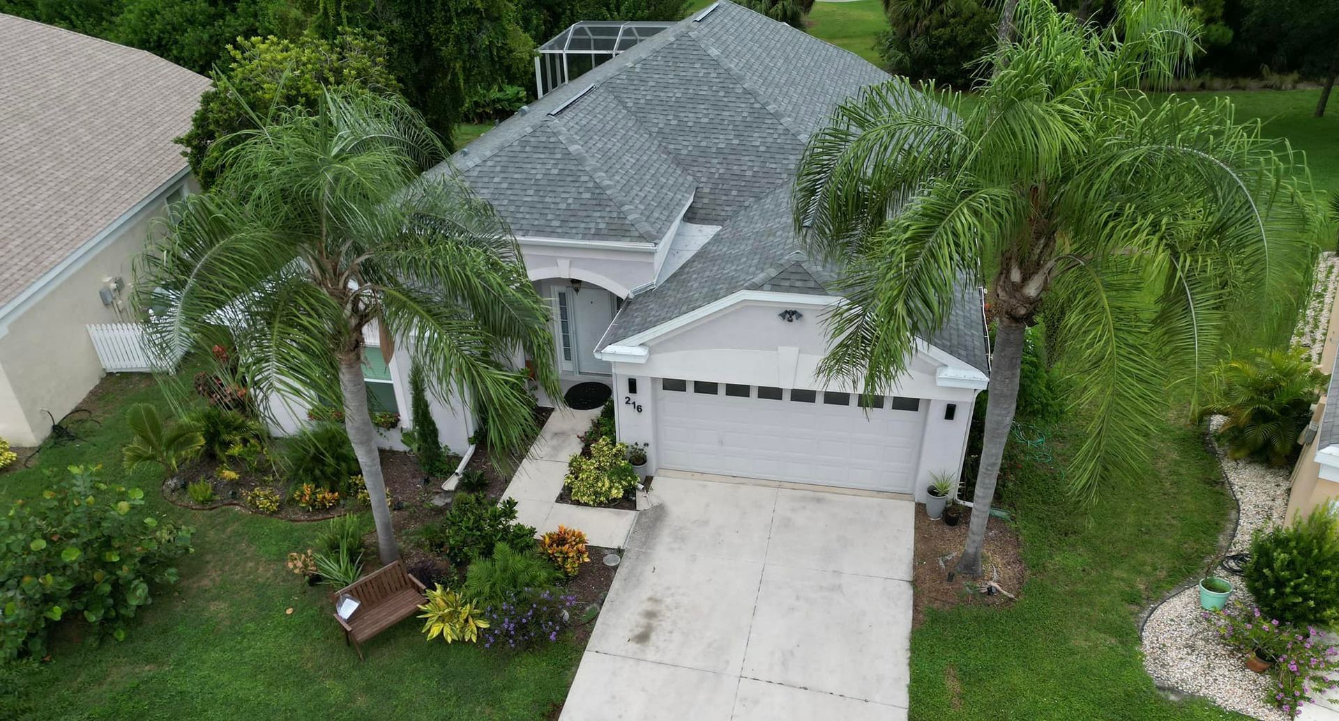 An aerial view of a house with a driveway and palm trees.