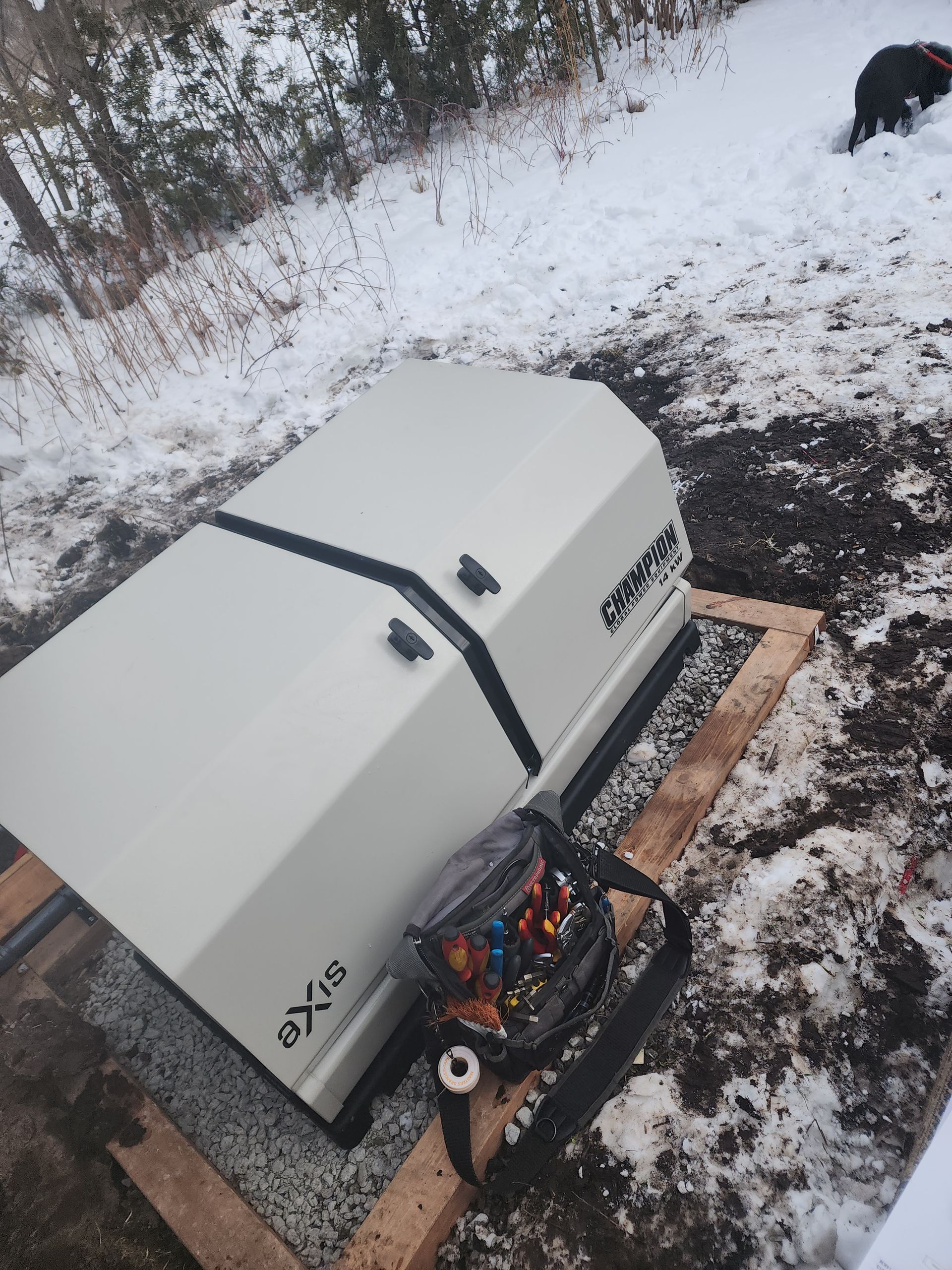 A generator in a snowy outdoor setting, with a carrying bag nearby.
