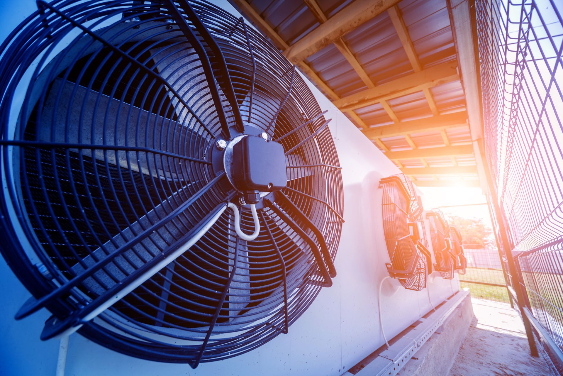 Large industrial fans mounted on a white wall, under sunlight.