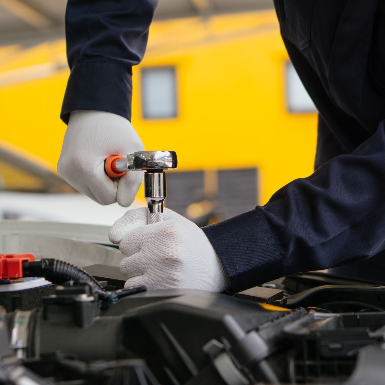 A man is working on a car engine with a wrench.