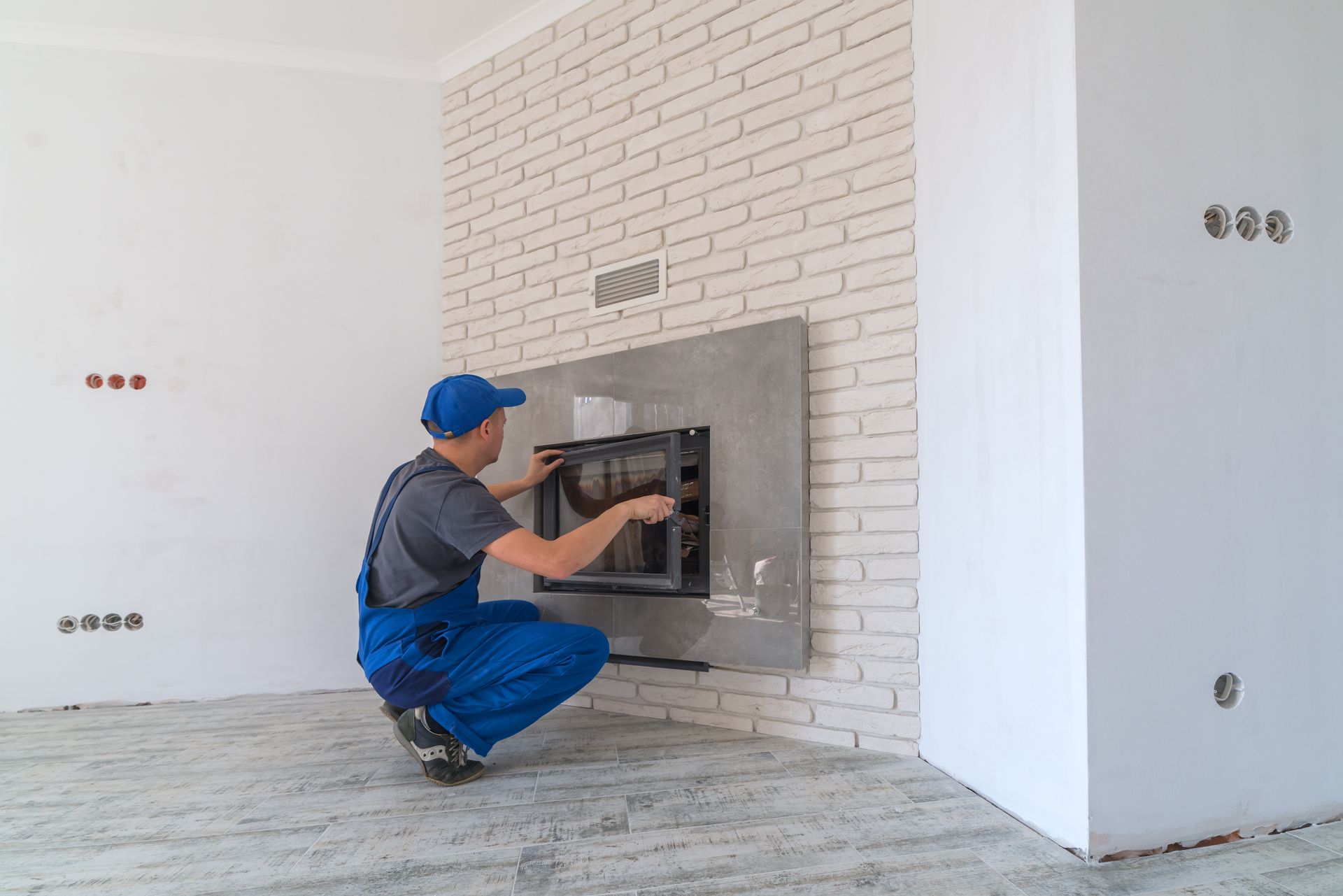A man is installing a fireplace in a living room.