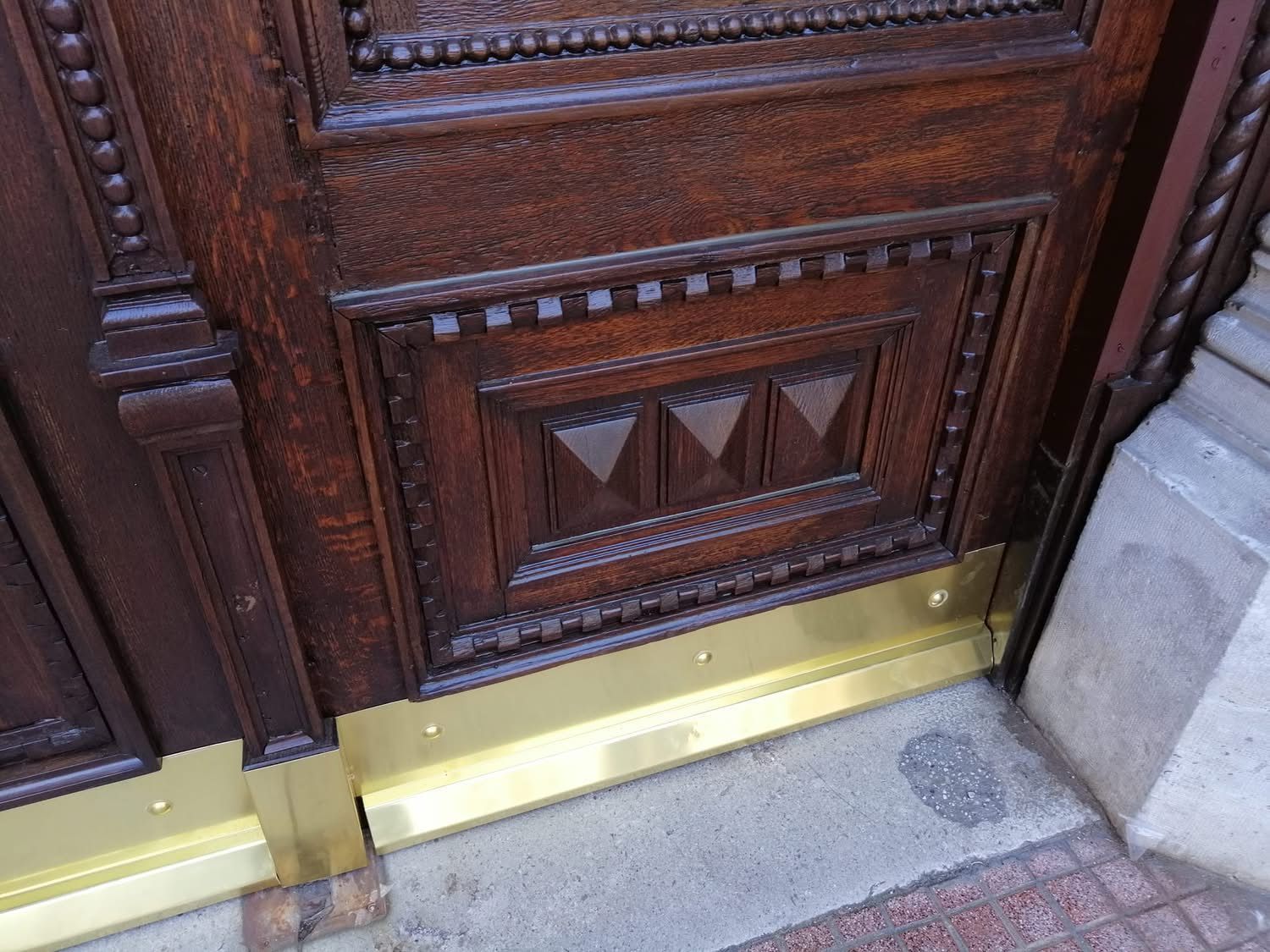 Primo piano di una porta di legno con finiture in ottone.