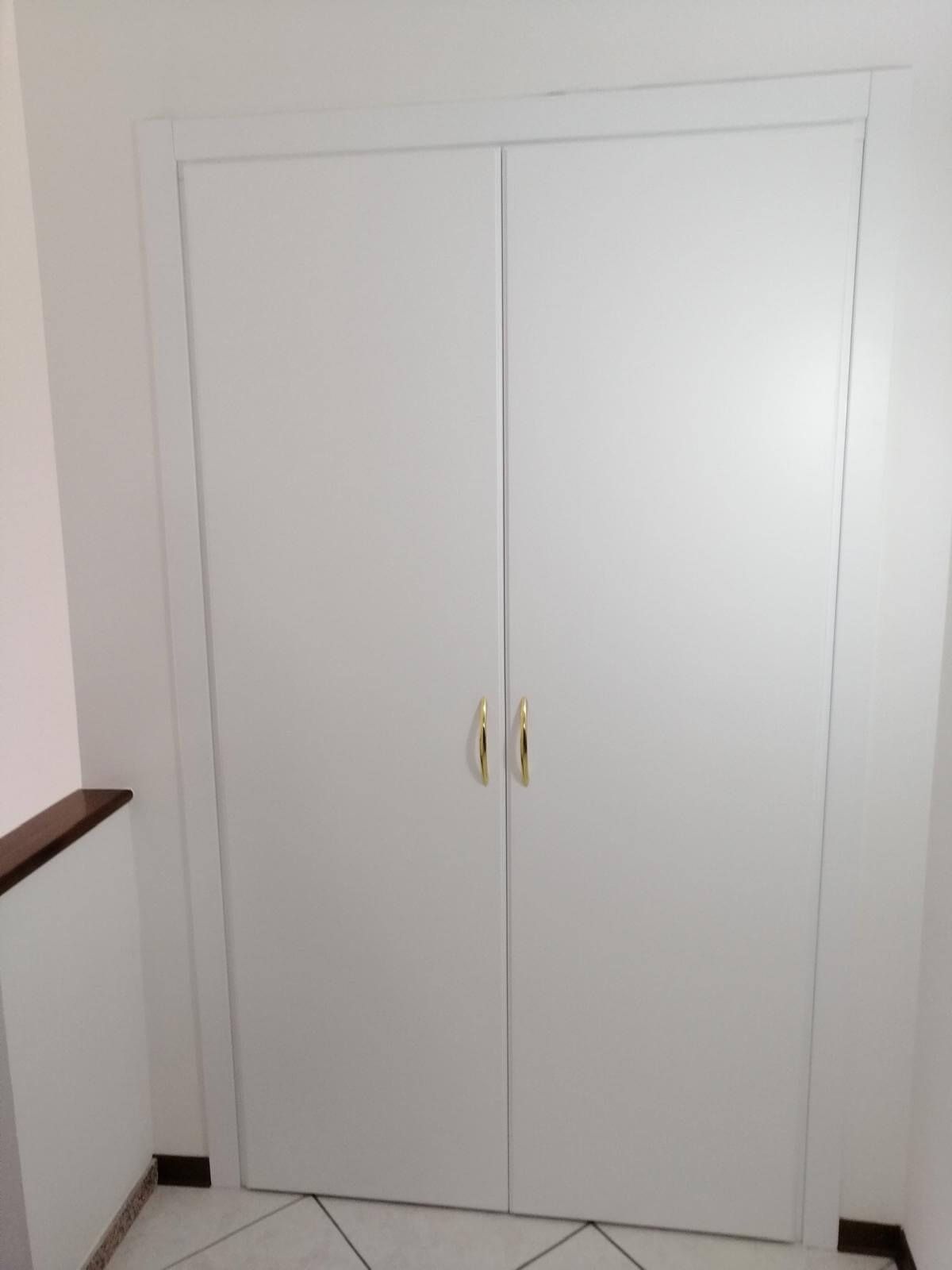 In una stanza c'è una porta bianca con maniglie dorate.