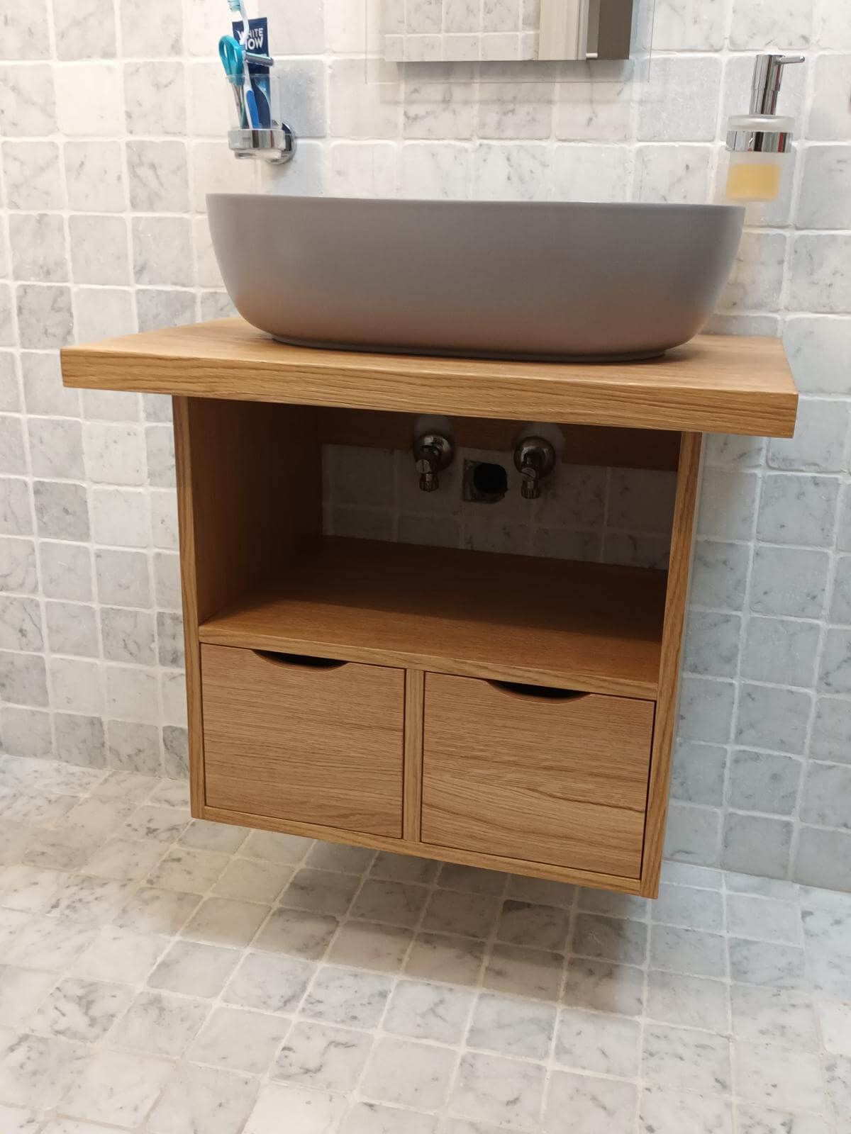 Un lavandino del bagno è appoggiato su una mensola di legno.