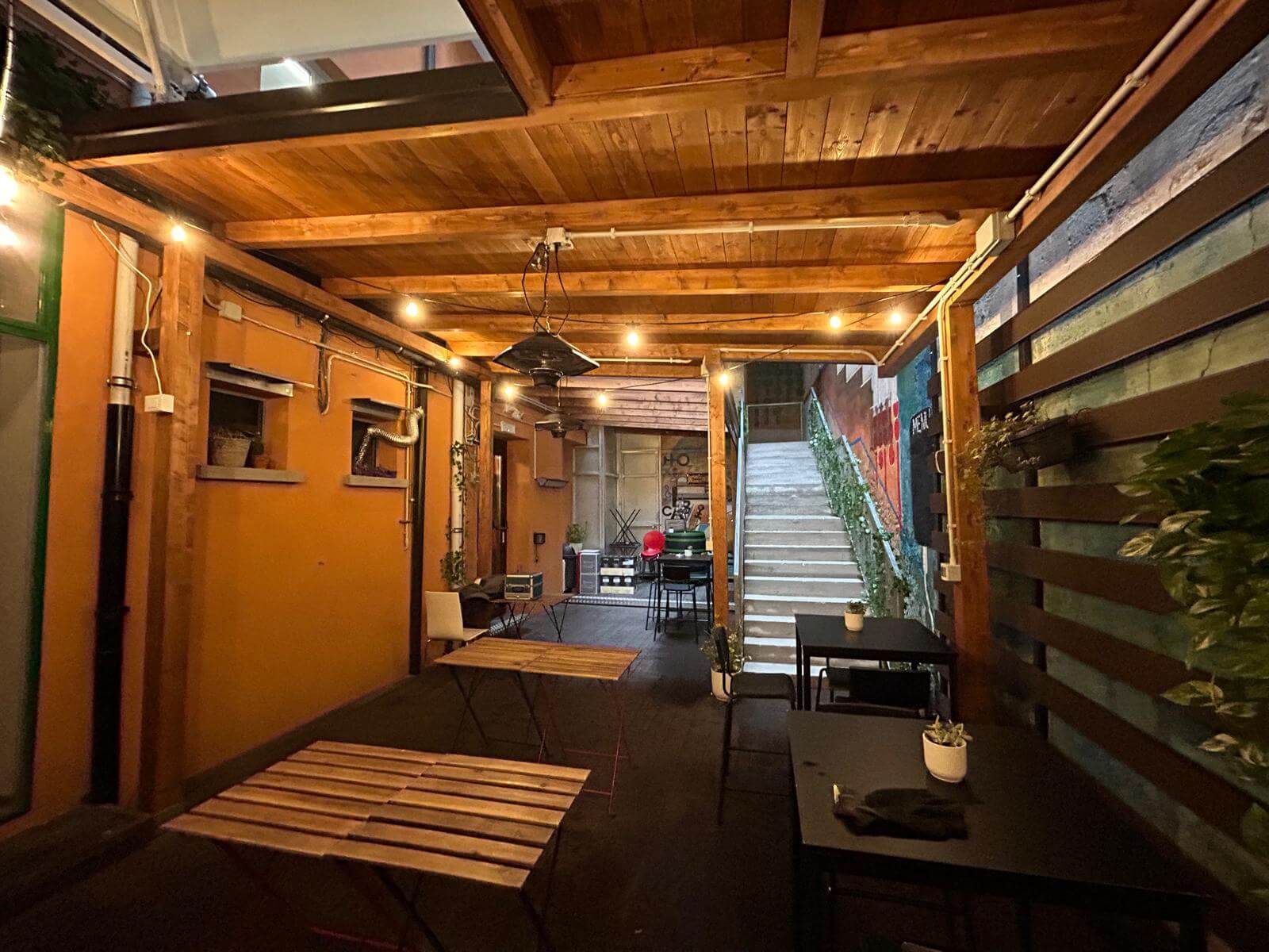 Una stanza con tavoli e sedie sotto un tetto di legno.