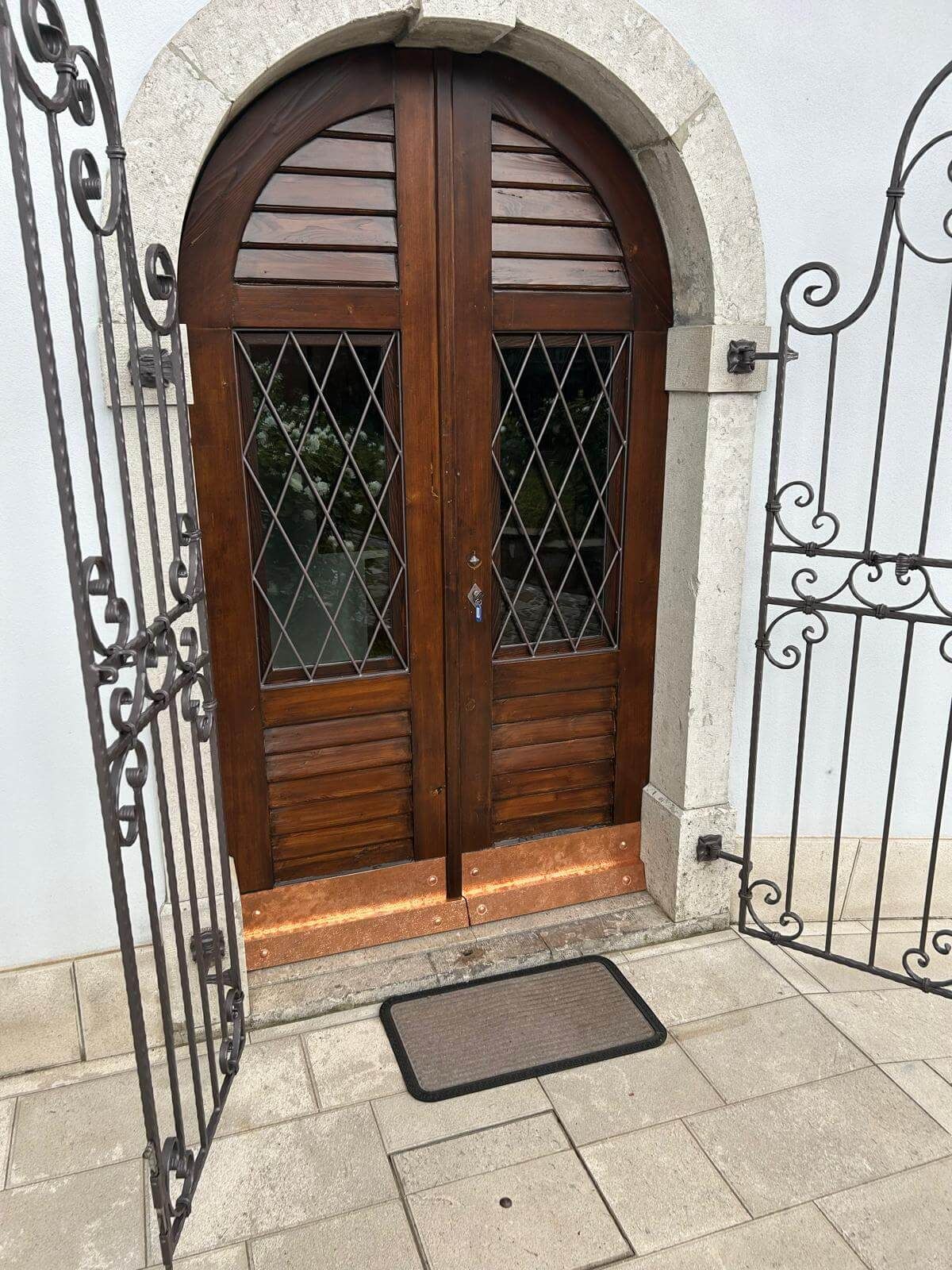 Una porta di legno con un cancello in ferro battuto e uno zerbino davanti.