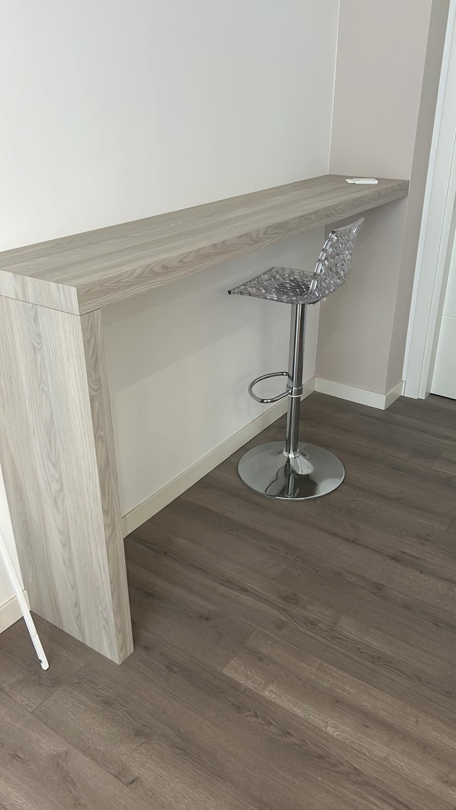 Uno sgabello da bar è appoggiato accanto a un tavolo di legno in una stanza.