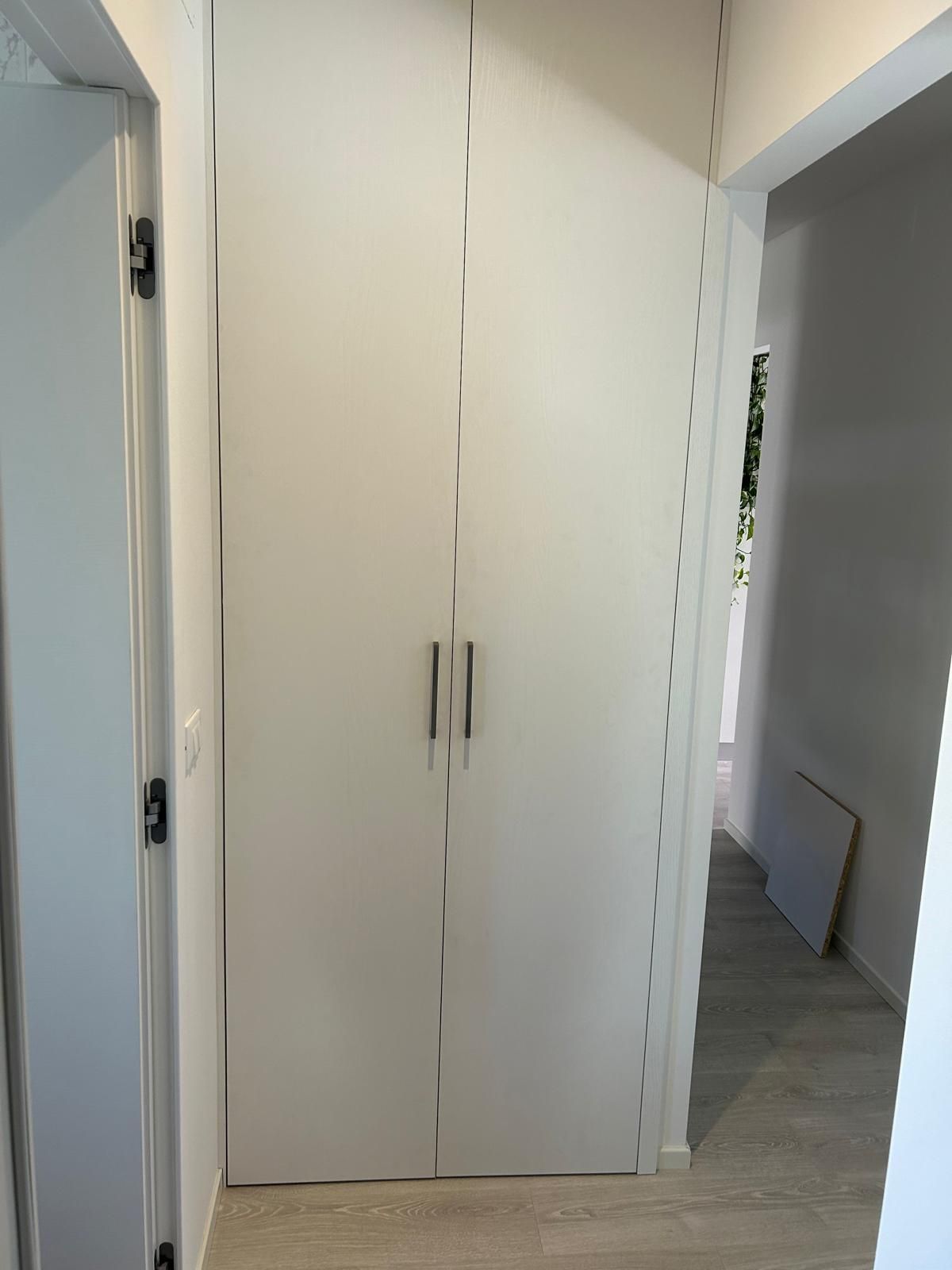 Un corridoio con una porta bianca e un pavimento in legno.