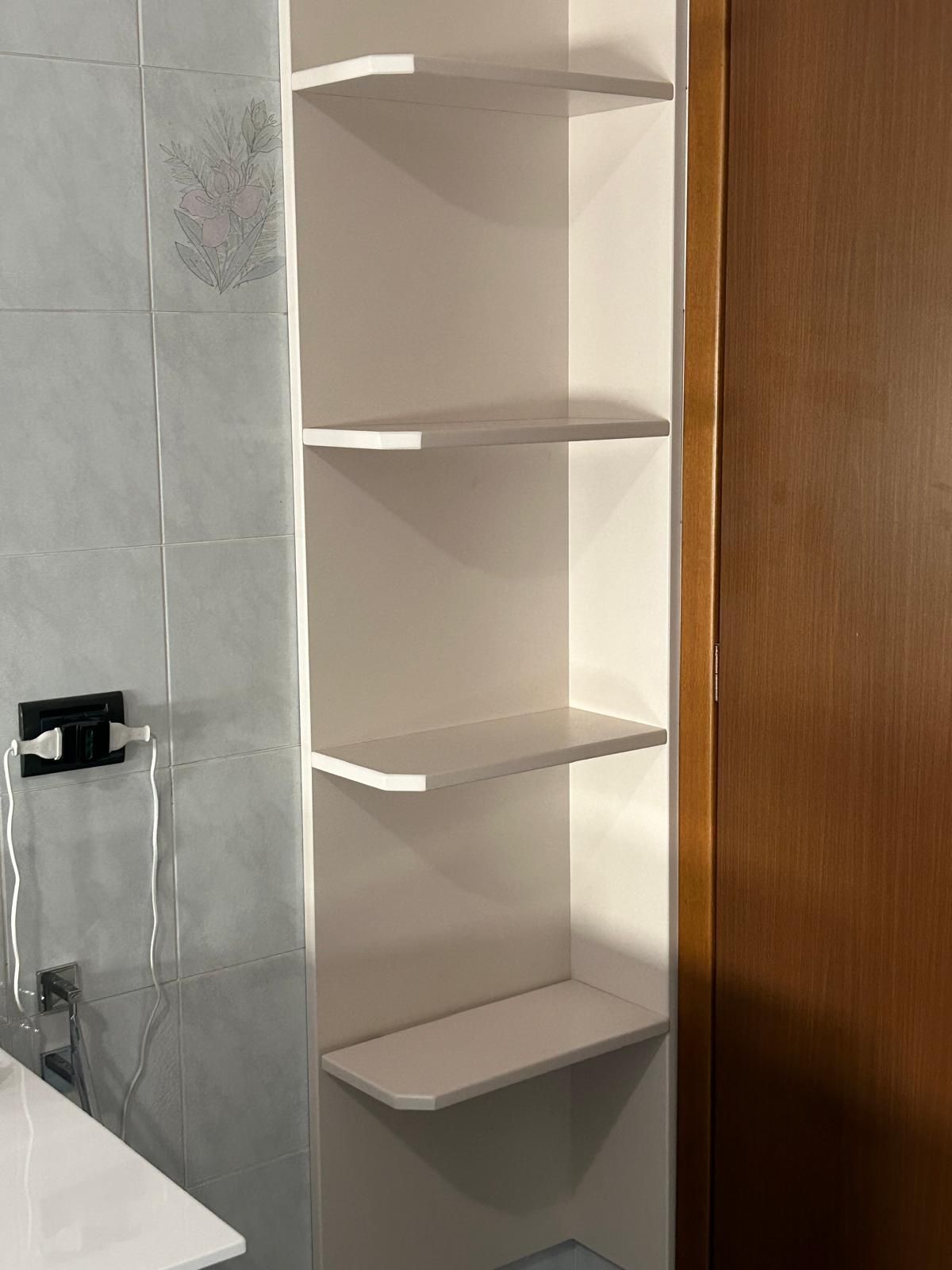 Un bagno con una mensola bianca e una porta di legno.