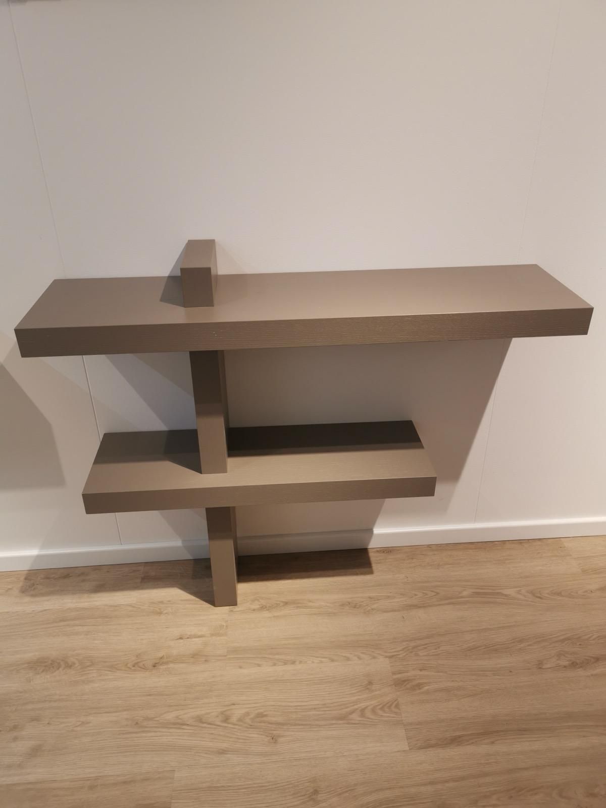 In una stanza c'è uno scaffale di legno appoggiato sul pavimento di legno.