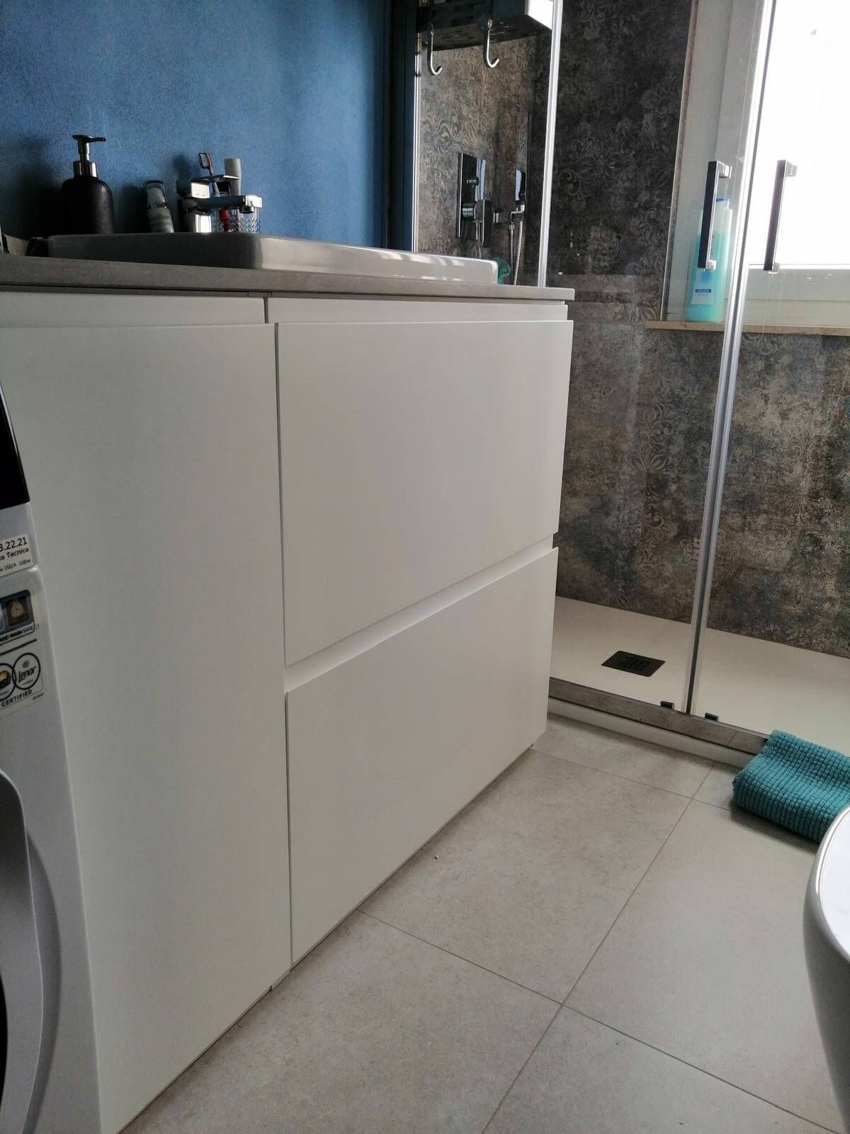 Un bagno con lavatrice, lavandino, wc e doccia.