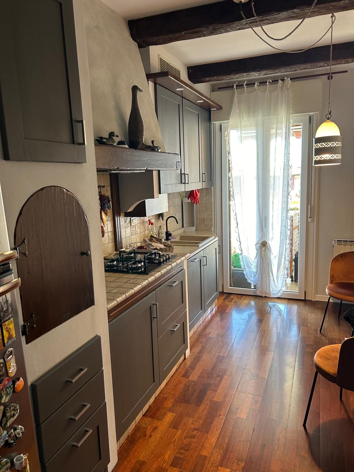 Una cucina con pavimenti in legno, mobili grigi e un forno.