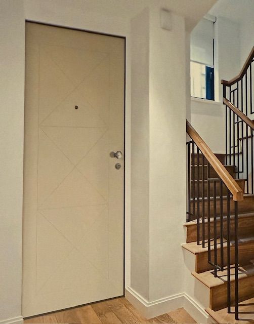 Un corridoio con scale e una porta bianca