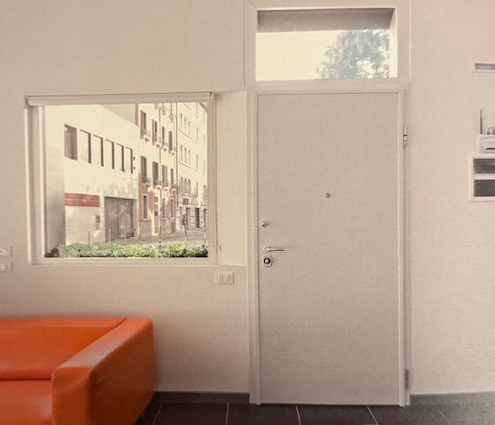 Un soggiorno con un divano arancione e una porta bianca.