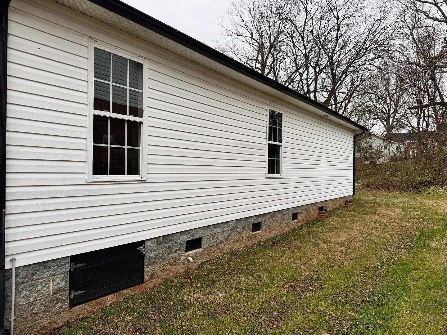 Side view of a white house with two windows, black trim, and a black door