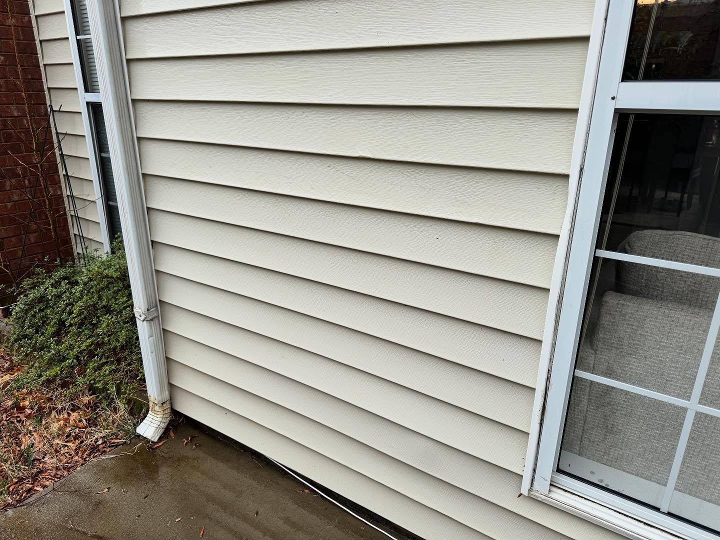 Beige siding on a building with a window. A white gutter runs along the side.