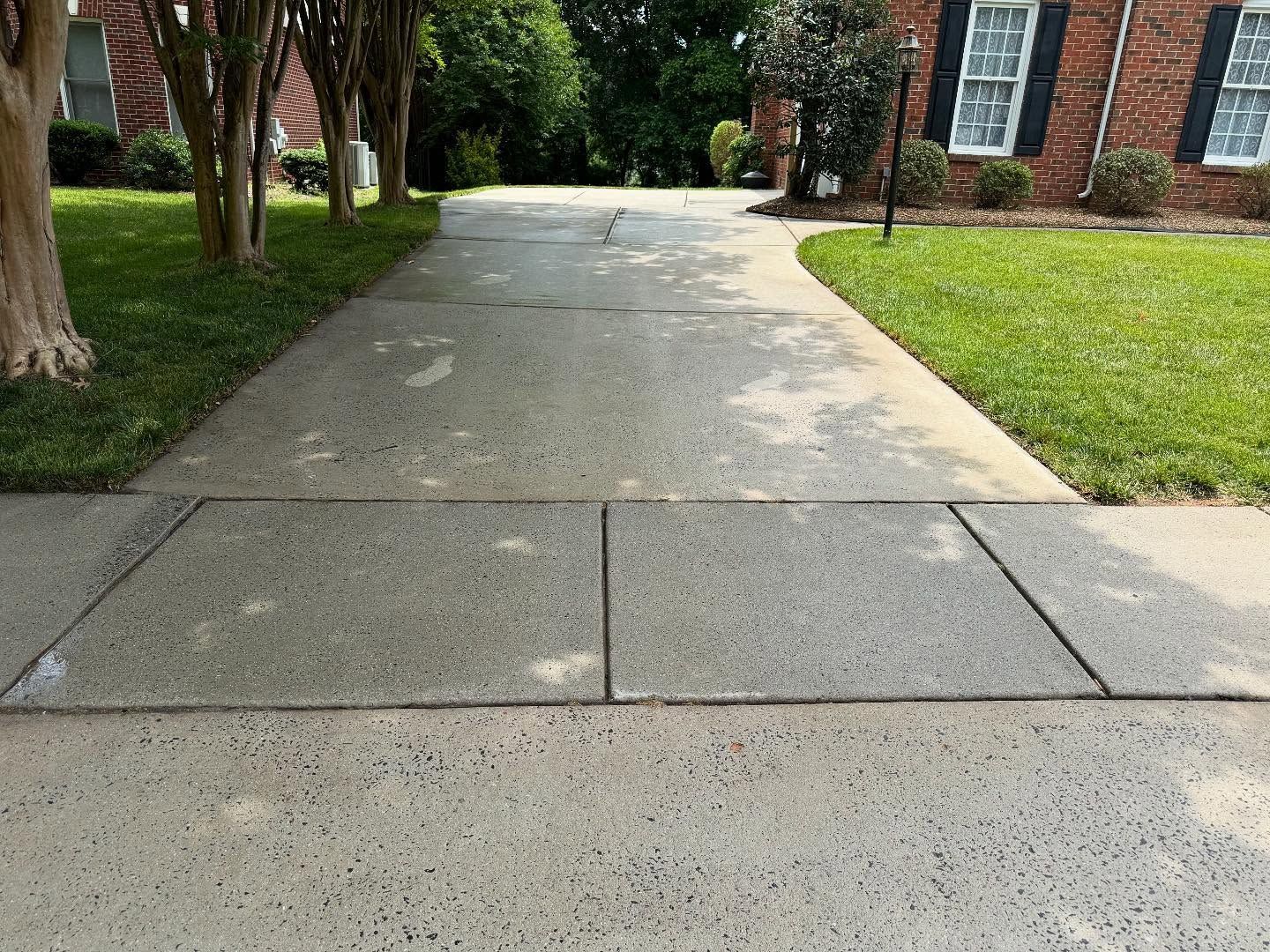 Brick walkway winding through a landscaped yard with green grass and brown mulch.