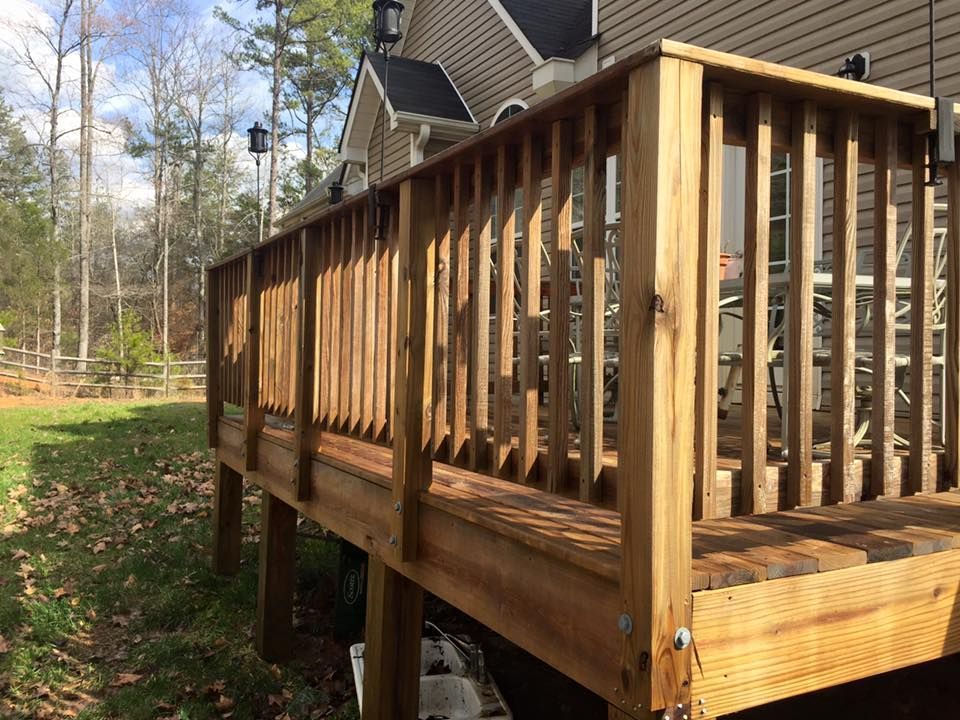 Wooden deck with railing extending from a house into a grassy yard. The deck is light brown.