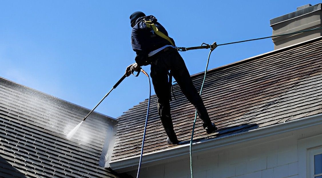 A pressure washer sprays water onto a brick surface, cleaning the grime. The cleaned area is lighter in color.