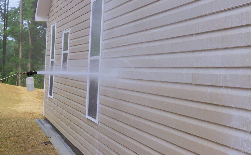 Pressure washing a wooden fence, revealing the clean, lighter wood on the right side.