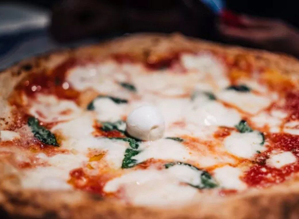 Un primo piano di una pizza con mozzarella e basilico su un tavolo.