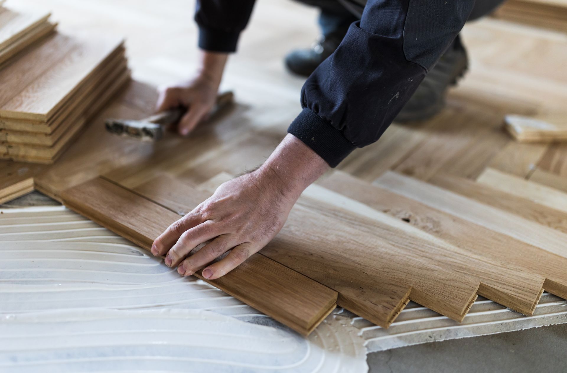 Experienced worker installing parquet boards in glue in new house.