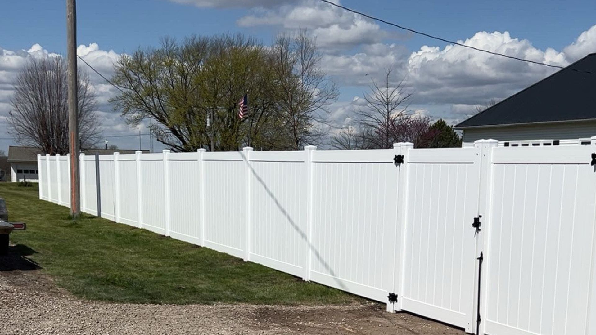 A white vinyl fence with a gate in front of a house.