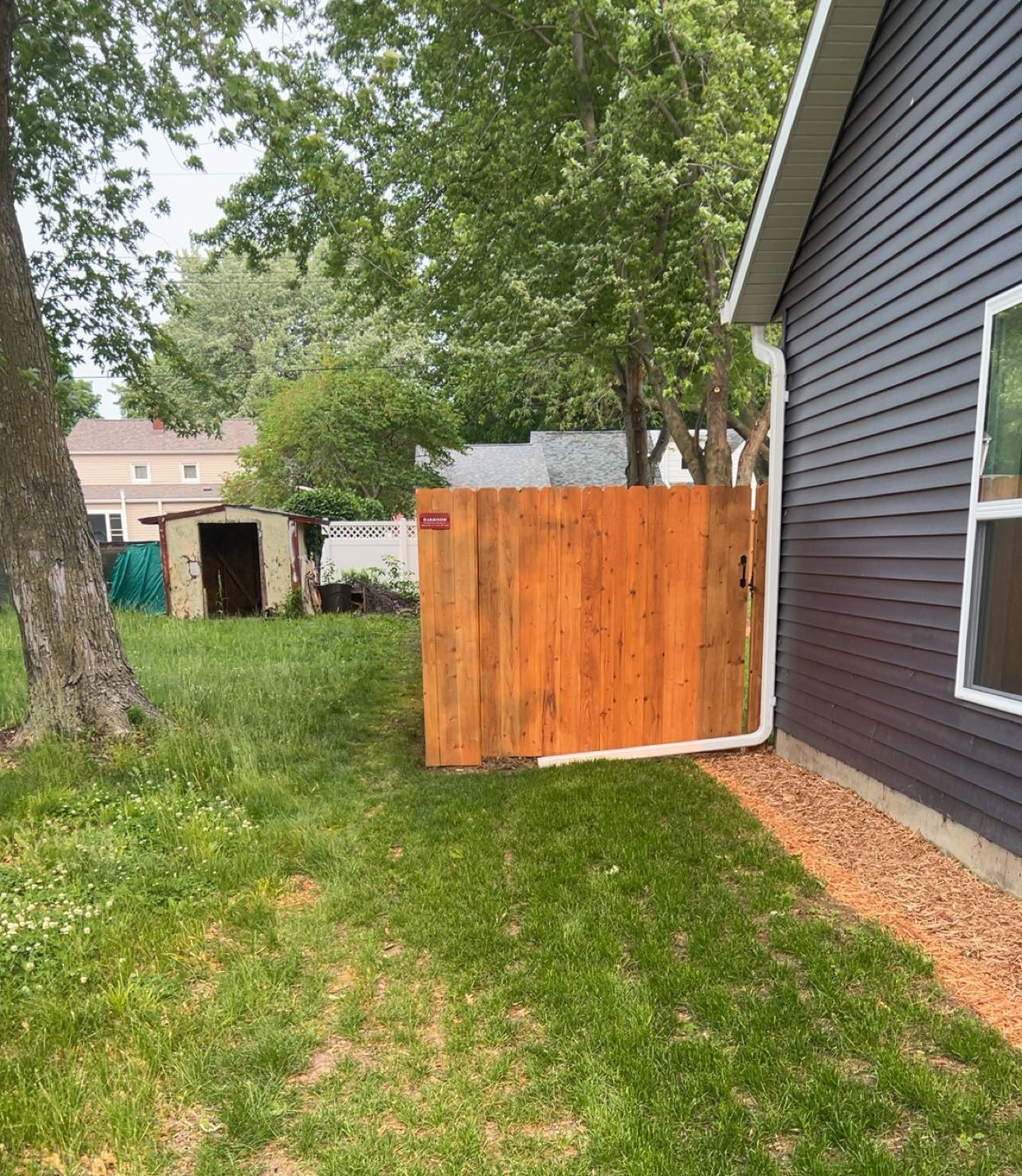A wooden fence is in the backyard of a house.