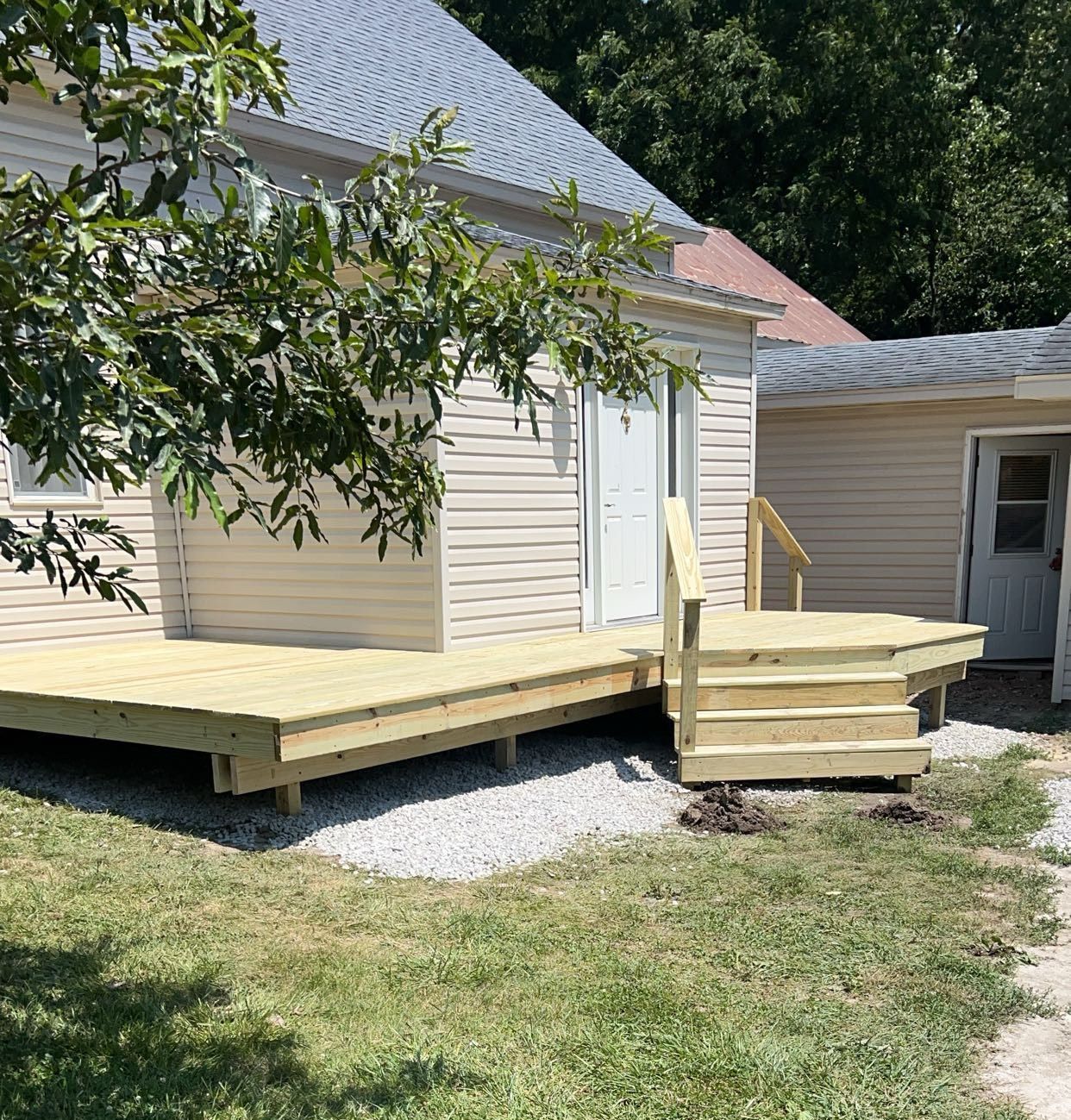 A house with a wooden deck and stairs in front of it.