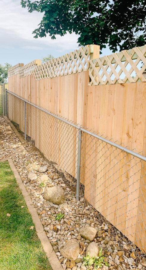 A wooden fence with a chain link fence in a backyard.