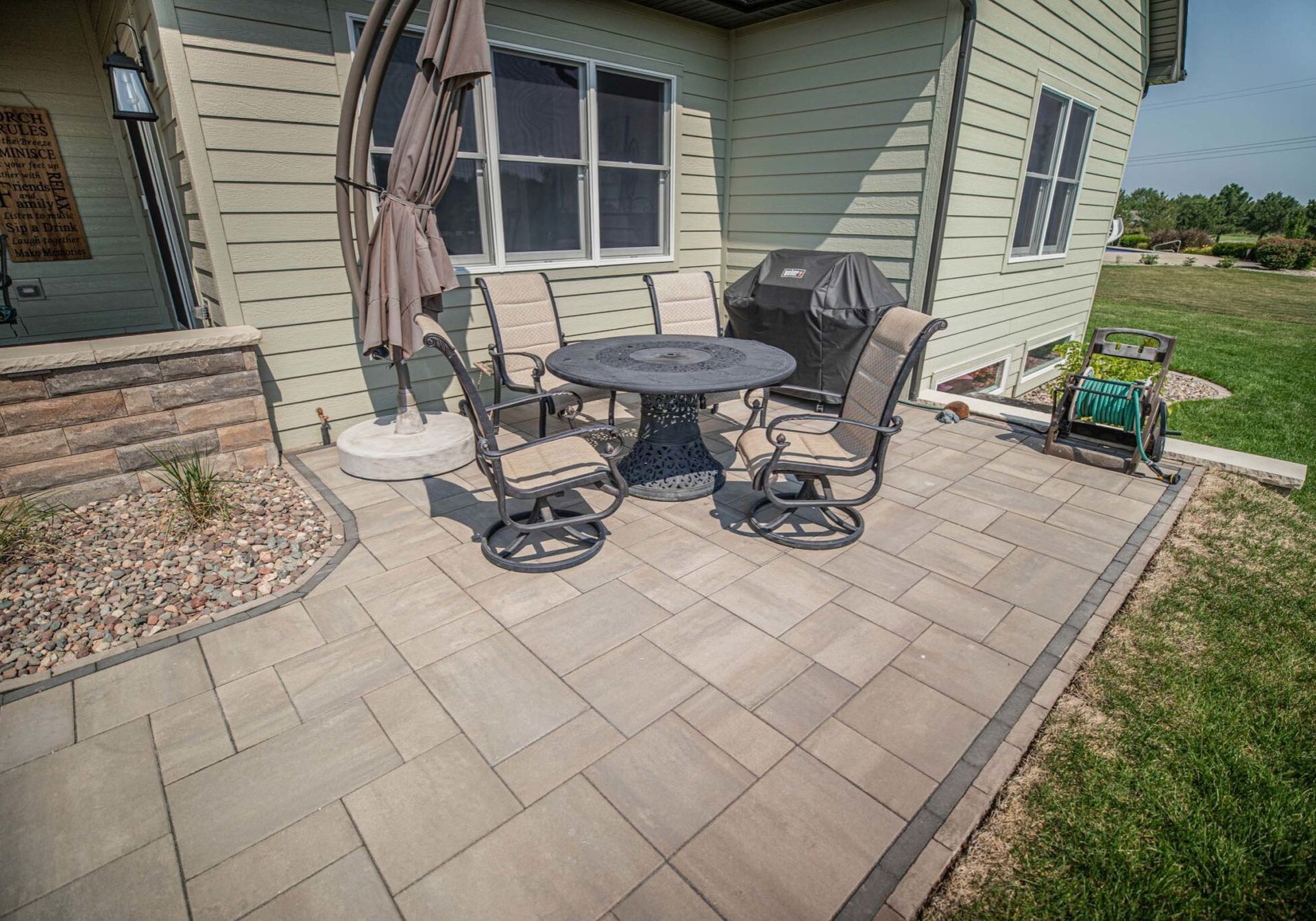 A patio with a table and chairs and an umbrella in front of a house.