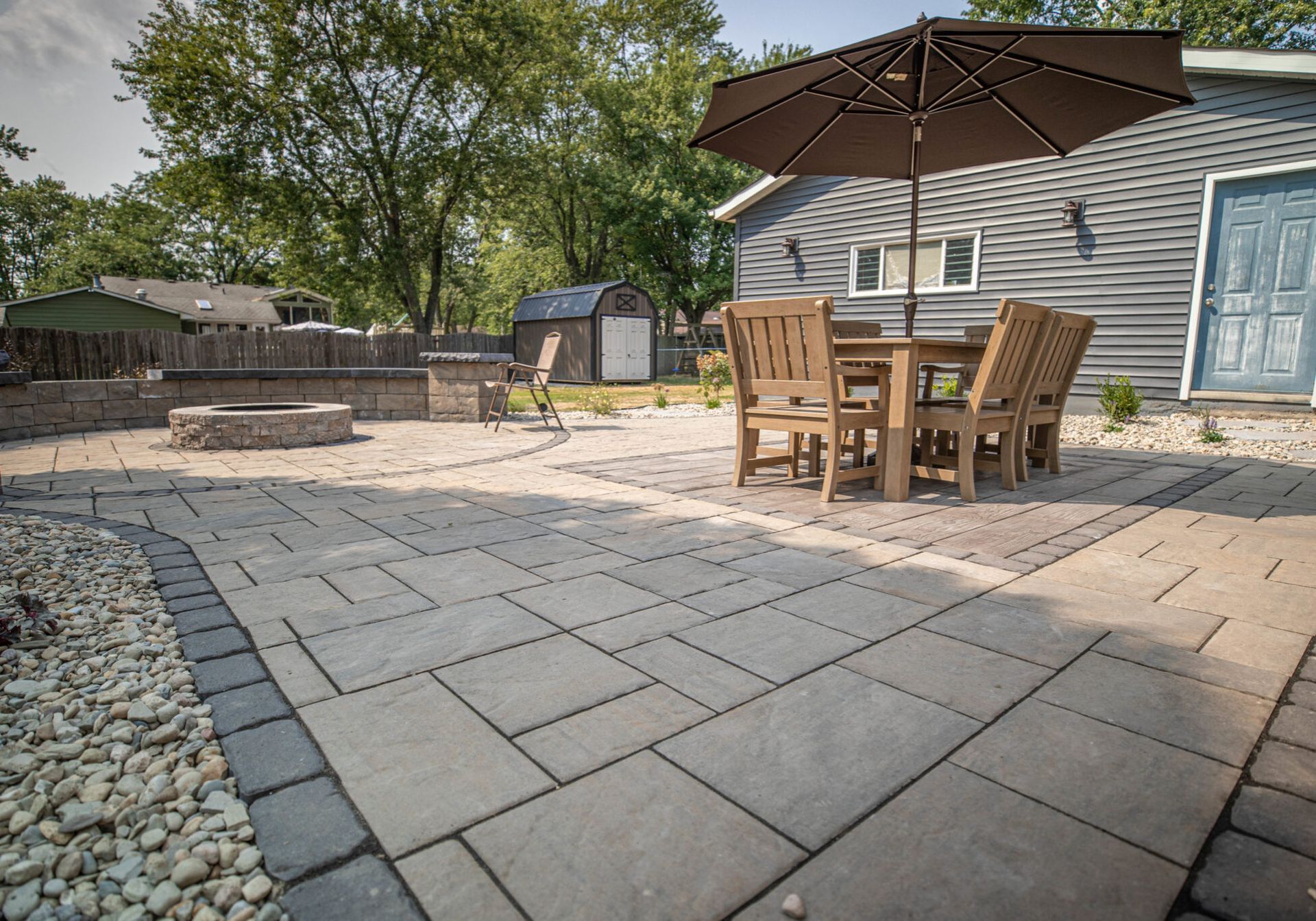 A patio with a table and chairs and an umbrella in front of a house.