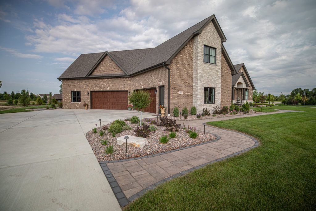 A large brick house with a large driveway in front of it.