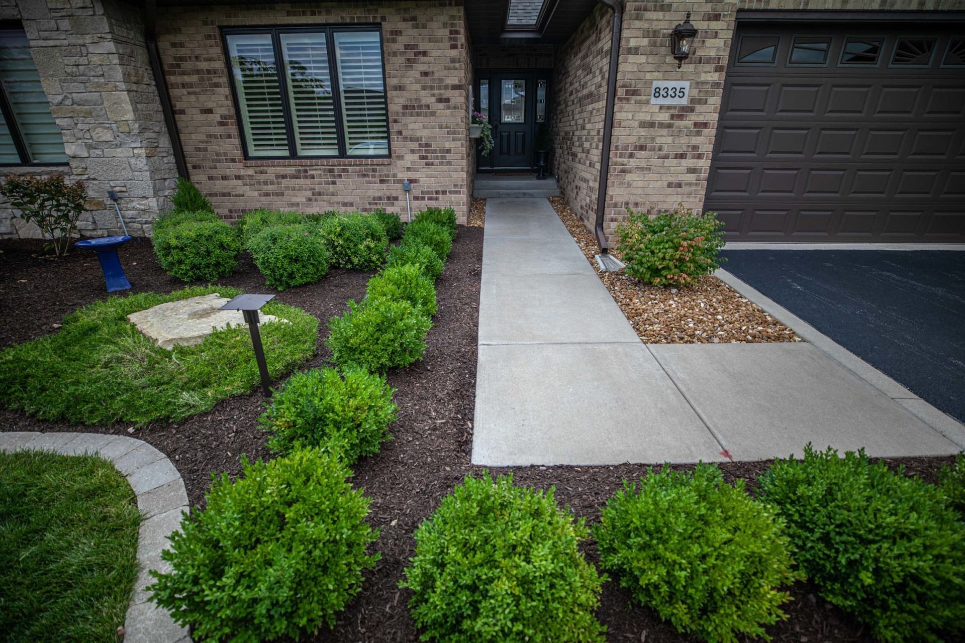 A brick house with a concrete walkway leading to the front door.