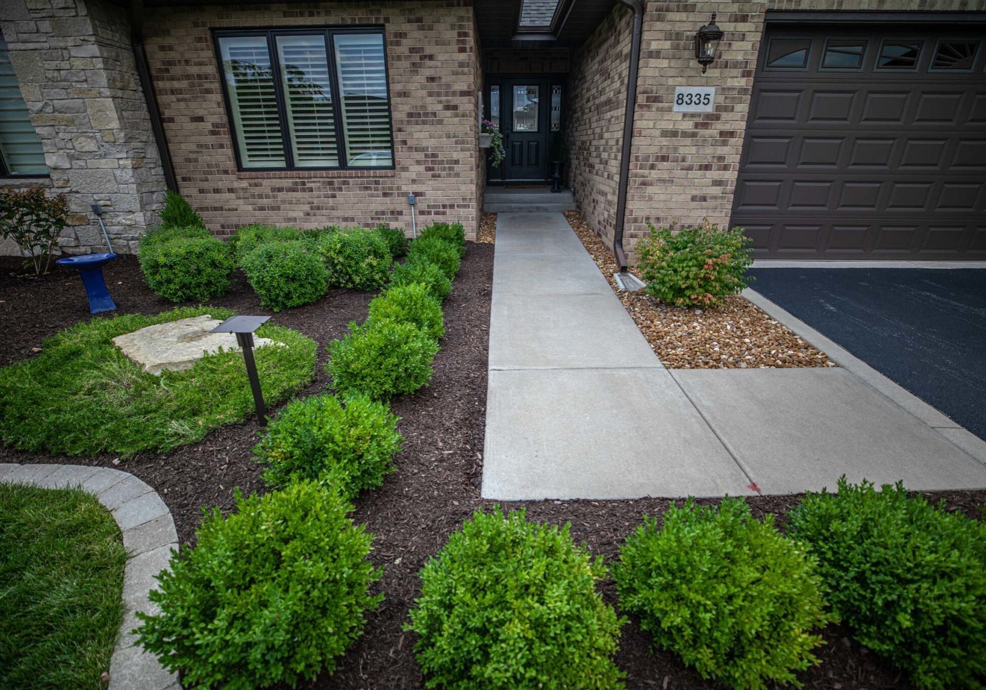 A brick house with a walkway leading to the front door and a garage.