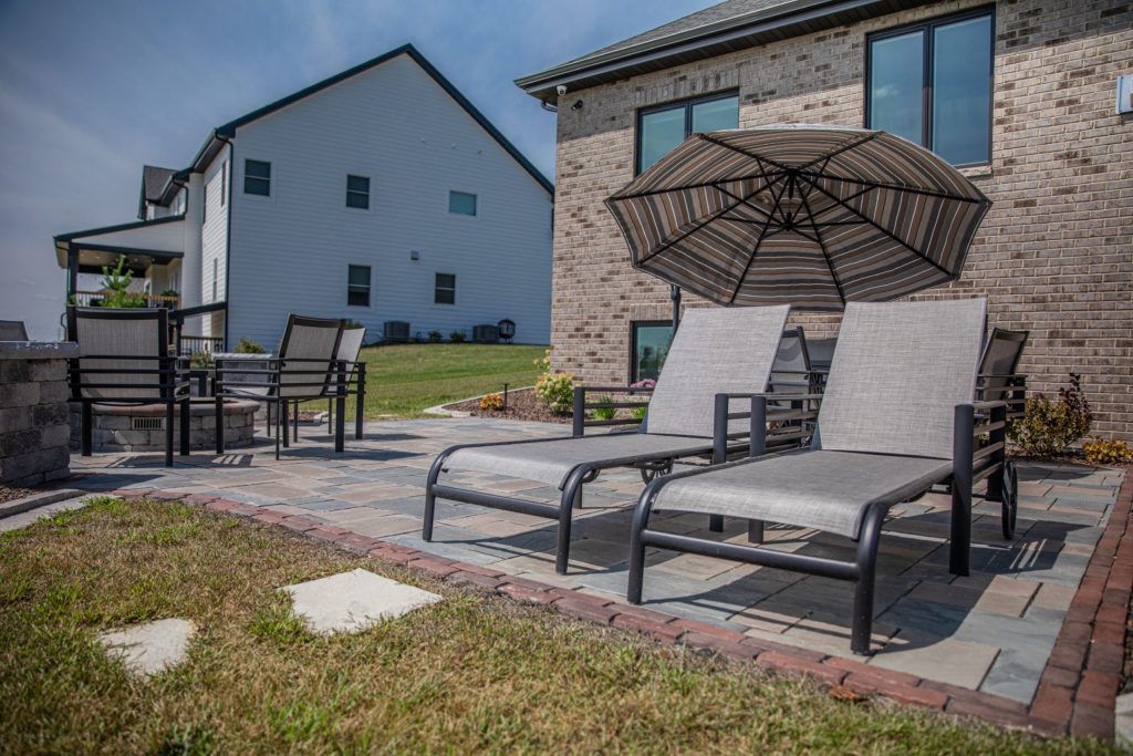 A patio with chairs and an umbrella in front of a house.