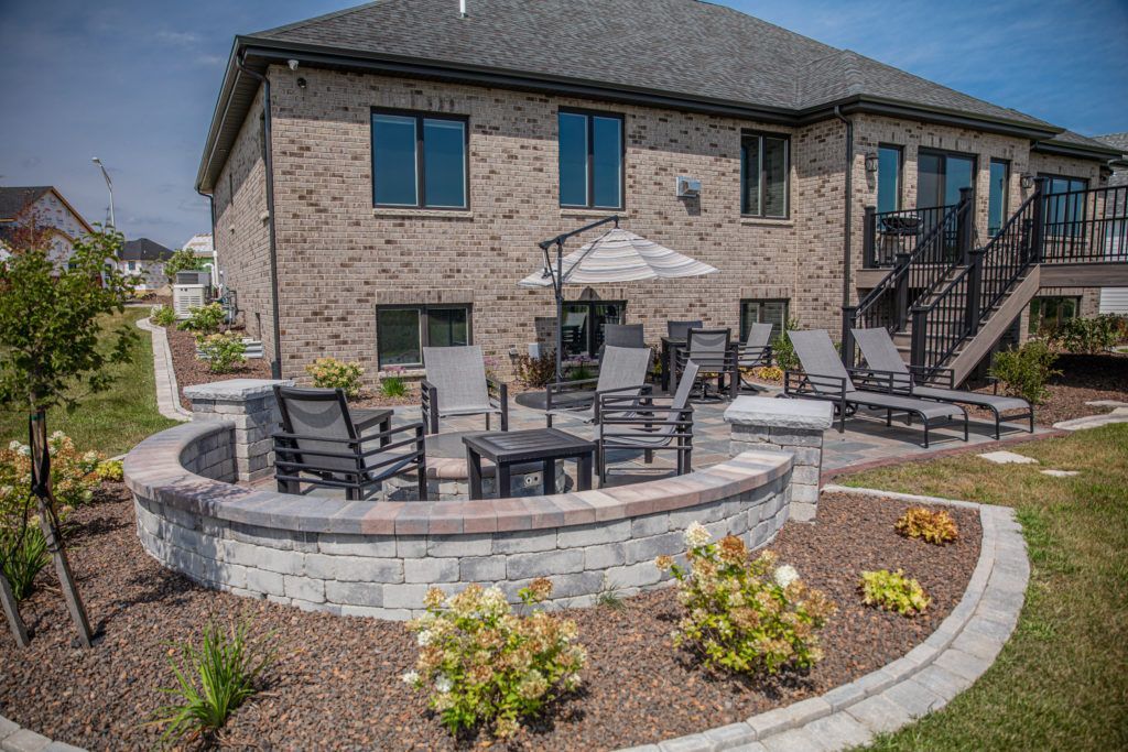 A large brick house with a patio area and a fire pit in front of it.