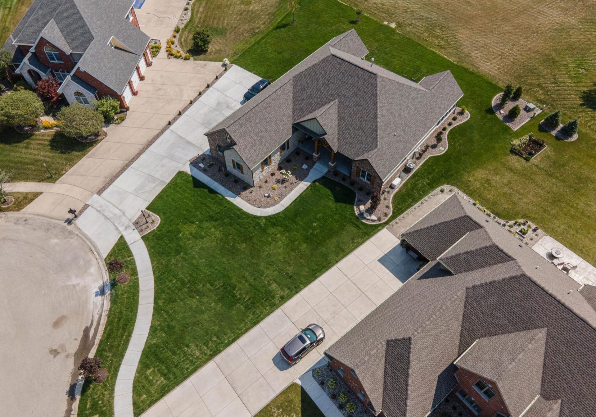 An aerial view of a residential neighborhood with a car parked in the driveway.