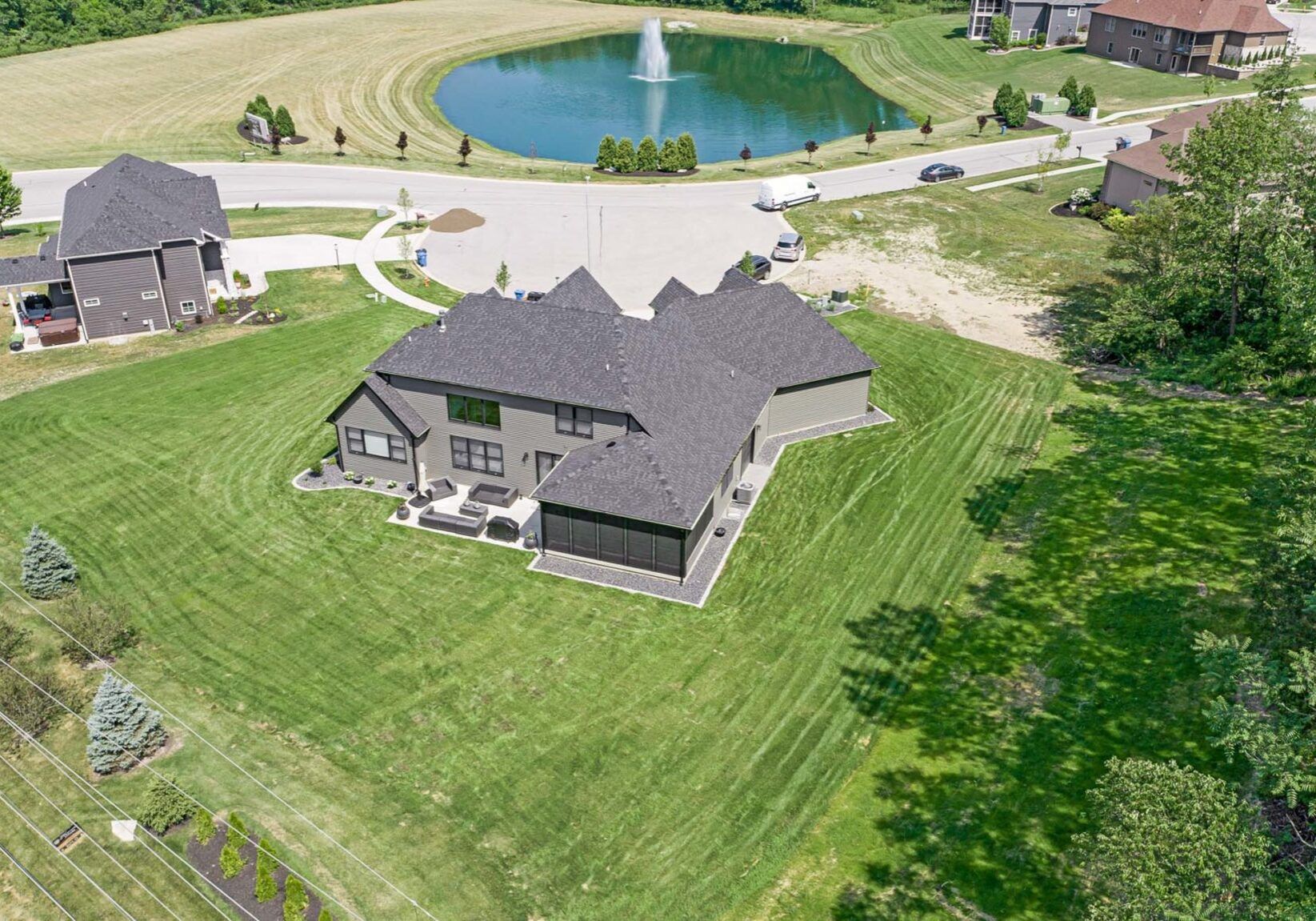 An aerial view of a large house with a pond in the background.