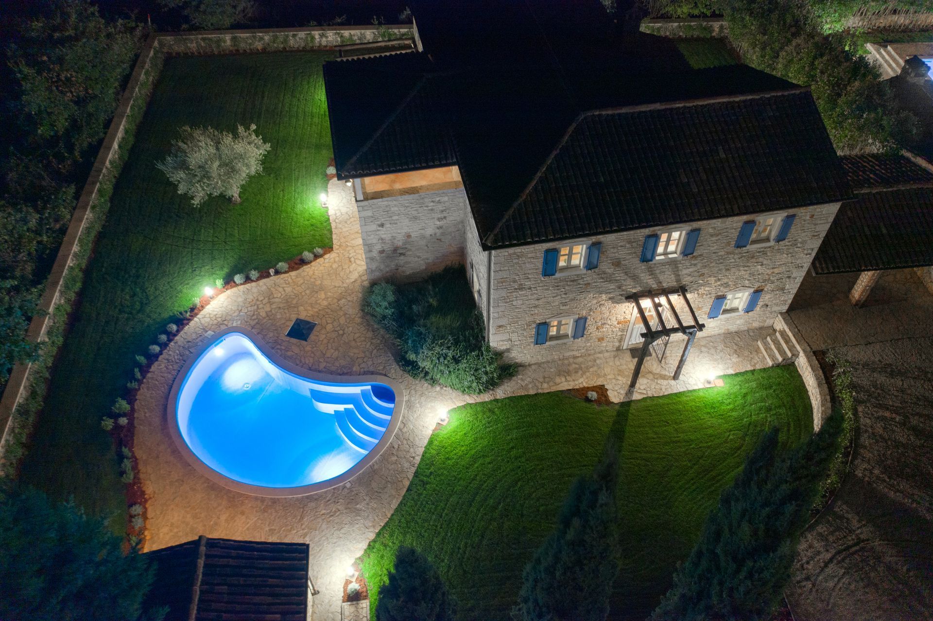 An aerial view of a house with a swimming pool in the backyard at night.