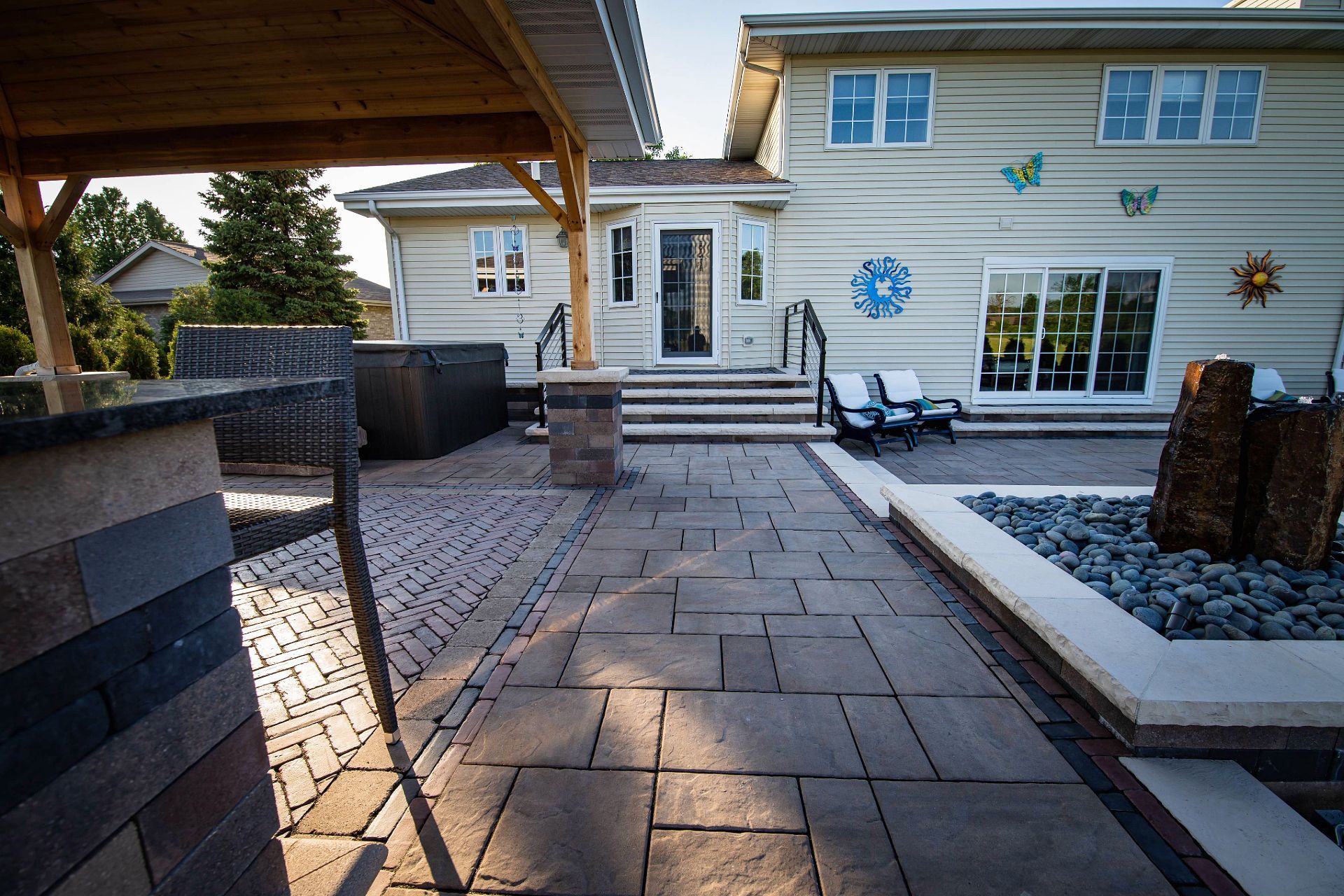 A large brick house with a large porch and steps is sitting on top of a lush green lawn.