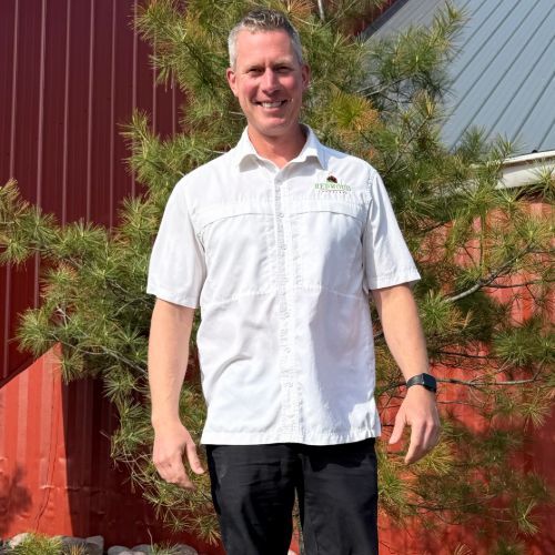 A man in a red shirt is standing in front of a red wall.