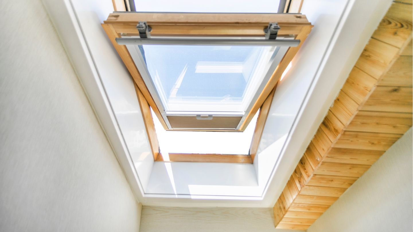 Skylight in a white room, open to the sky. Wooden frame, natural light.