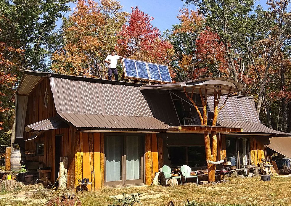Man standing on top of a building next to a solar panel. 