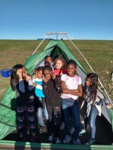 Kids standing outside of a tent